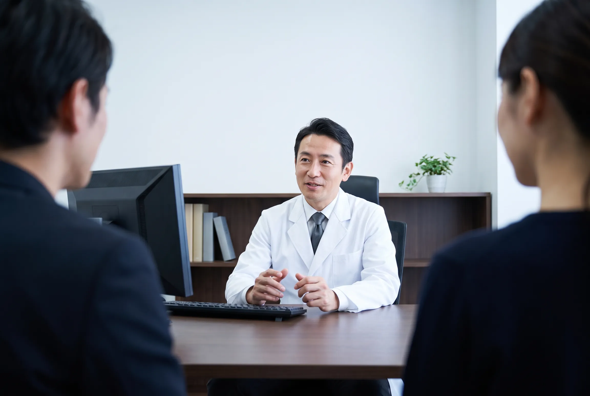A specialist speaking with two patients across his desk at Victoria Medical Group